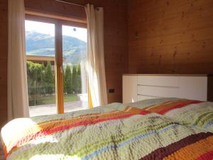 a bedroom with a bed and a large window at Chalet Finkennest in Neukirchen am Großvenediger