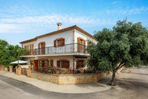 a white house with a balcony and a tree at Sa Fonteta Cala Morlanda in S'Illot