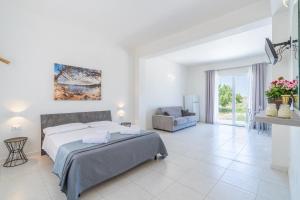 a white bedroom with a bed and a chair at L' oro dei Magi San Lorenzo in Reitani