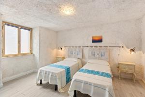 two beds in a room with white walls at Casa Rocca in Bosa