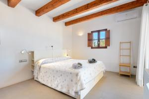 a white bedroom with a white bed with a wooden ceiling at Casa S'Olibassa in La Mola +17 photos