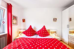 a bedroom with a red bed with red and white pillows at Ferienwohnung Schwarzwaldhirsch in Unterkirnach