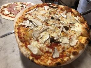 a pizza with mushrooms on it sitting on a table at Lovers' Nest - Unità 1 in Baiardo +37 photos