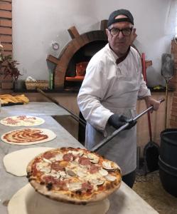 a man holding a pizza on top of a table at Lovers' Nest - Unità 1 in Baiardo