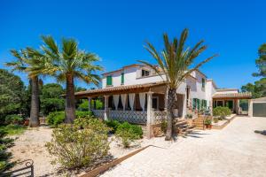 a house with palm trees in front of it at Villa Can Neo in Santanyi