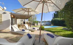 a patio with white chairs and an umbrella and a pool at Collet De Manacor in Manacor