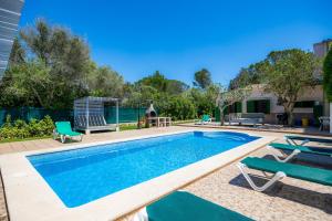 a swimming pool with two chairs next to a house at Villa Can Neo in Santanyi