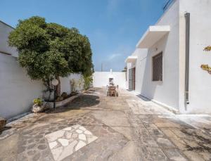 a courtyard of a white building with a tree at Villa del Mirto Punta Prosciutto in Torre Lapillo