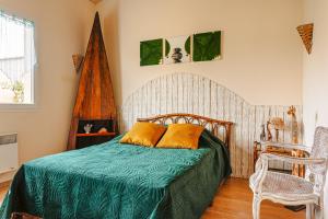 a bedroom with a bed with a green blanket and a chair at Charmant Gite Egaux De Chambon in Chambon