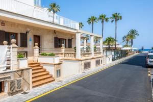 a building on the side of a street with palm trees at Dofí in Cala Millor