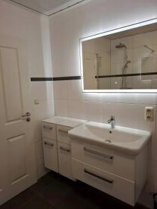 a white bathroom with a sink and a mirror at Ferienhaus Timeout in Friedrichskoog +36 photos