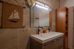 a bathroom with a sink and a sail boat on the wall at La Voûte Des Oliviers in Bessas +13 photos
