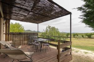 a patio with a table and chairs on a deck at La Voûte Des Oliviers in Bessas