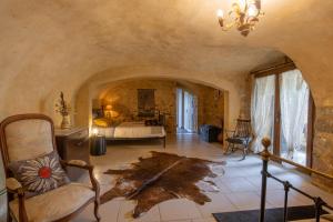 a bedroom with a bed and a chair in a room at La Voûte Des Oliviers in Bessas