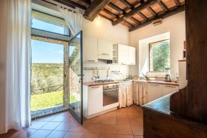 a kitchen with a large window and a large kitchen with white cabinets at Podere Montorgialino in Murlo +20 photos