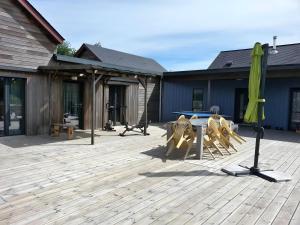 a patio with a table and chairs and an umbrella at Au P'tit Venton - Maison Écologique in La Jaille-Yvon