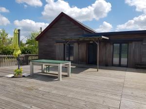a ping pong table on a deck in front of a house at Au P'tit Venton - Maison Écologique in La Jaille-Yvon