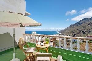 a table and chairs on a balcony with a view of the ocean at House in Anaga in Almáciga