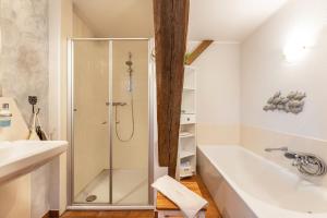 a bathroom with a shower and a white bath tub at Haevn-Erholung, Fewo Deichblick in Reußenköge +27 photos