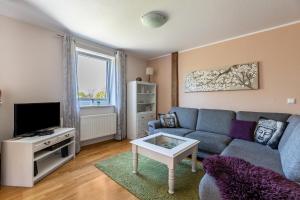 a living room with a couch and a tv at Haevn-Erholung, Fewo Deichblick in Reußenköge