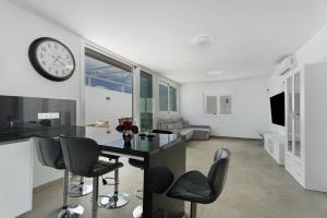 a living room with a clock on the wall and a table at Villa Violeta in Costa Del Silencio