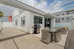 a patio with a table and chairs and a grill at Villa Violeta in Costa Del Silencio
