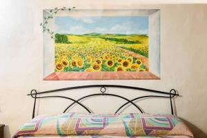 a painting of a field of sunflowers is above a bed at Armaiolo Relax in Rapolano Terme