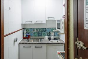 a small kitchen with white cabinets and a sink at Triana Historic Center in Seville