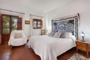 a bedroom with a white bed and a chair at Casa de la Fuente in Bubión