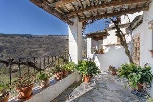 a balcony of a house with potted plants at Casa de la Fuente in Bubión