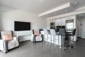a living room with a bar with chairs and a tv at Penthouse with private pool in Málaga