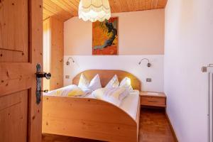a bedroom with a wooden bed with white pillows at Gamperhof Apartment Planet in Collepietra