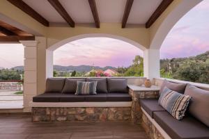 a porch with a couch and an arched window at Villa Logas Hill in Peroulades