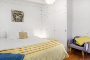 a white bedroom with a bed and a chair at Sunset Cliffs By Slice Of Heaven in Ribeira Brava