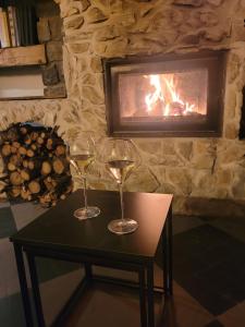two glasses of wine on a table in front of a fireplace at Le Saint Marquan in Brantes