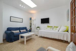 a living room with a blue couch and a tv at Bungalow Playa Bastián in Costa Teguise +17 photos