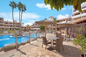 a resort with a pool and a table with chairs and umbrellas at Cathamarcella in San Miguel de Abona