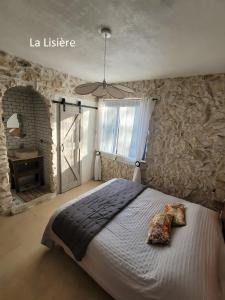 a bedroom with a large bed and a stone wall at Le Saint Marquan in Brantes