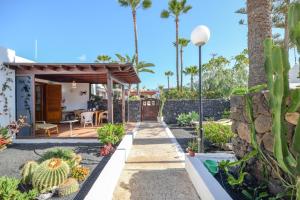 a garden with a pergola and palm trees at Bungalow Playa Bastián in Costa Teguise