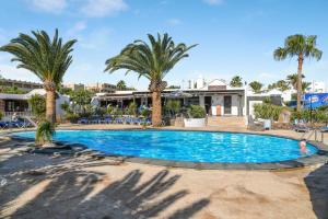 a swimming pool with palm trees in a resort at Bungalow Playa Bastián in Costa Teguise