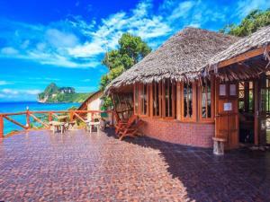 a building with a straw roof with the ocean in the background at Phuphaya Seaview Adults Only in Phi Phi Islands