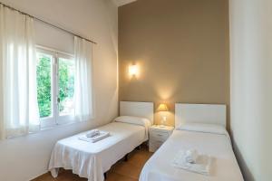 two twin beds in a room with a window at Villa Mariola in Sant Lluis +18 photos