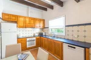 a kitchen with wooden cabinets and a sink and a window at Villa Mariola in Sant Lluis
