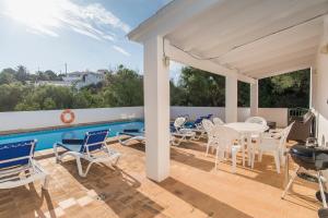 a patio with chairs and a table and a pool at Villa Mariola in Sant Lluis
