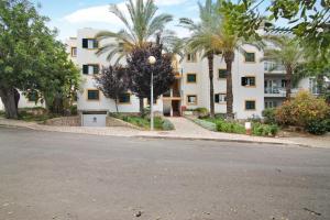 an empty street in front of a building with palm trees at Apartamento Tavirasol in Tavira