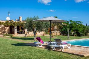 two chairs and an umbrella next to a swimming pool at Ca Sa Padrineta in Capdepera