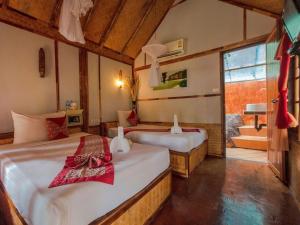 a bedroom with two beds and a bathroom with a tub at Phuphaya Seaview Adults Only in Phi Phi Islands