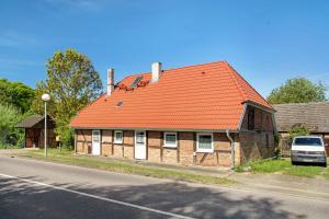 an orange roofed house on the side of a street at Ferienwohnung Alte Bauernkate in Süderholz