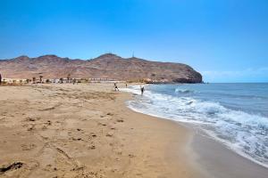 a beach with people walking on the sand and the ocean at Casa Rosi in Gran Tarajal