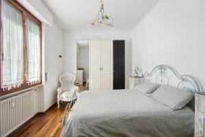 a white bedroom with a bed and a chandelier at Lo scoglio in Bogliasco